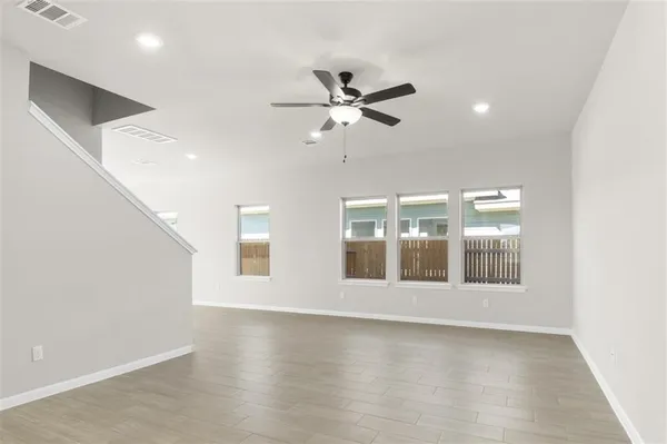 a view of an empty room with a window and wooden floor