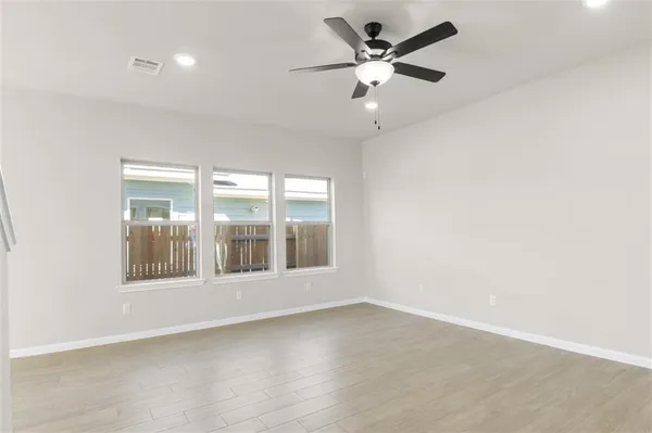 an empty room with wooden floor and windows