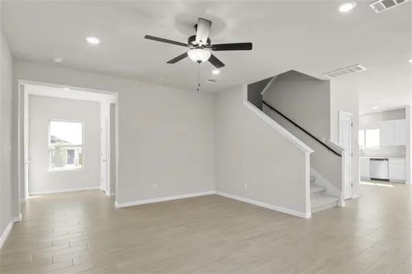 an empty room with wooden floor fan and windows