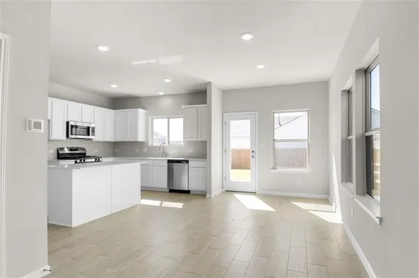 a large kitchen with kitchen island a sink a stove a refrigerator and white cabinets