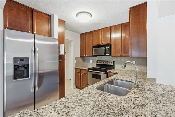 a kitchen with granite countertop stainless steel appliances a refrigerator stove and sink