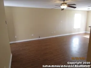 en empty room with wooden floor fan and window