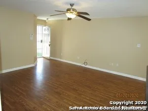 an empty room with wooden floor fan and windows