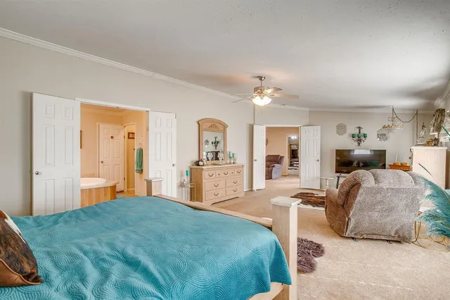 a spacious bedroom with a bed a chandelier and dresser