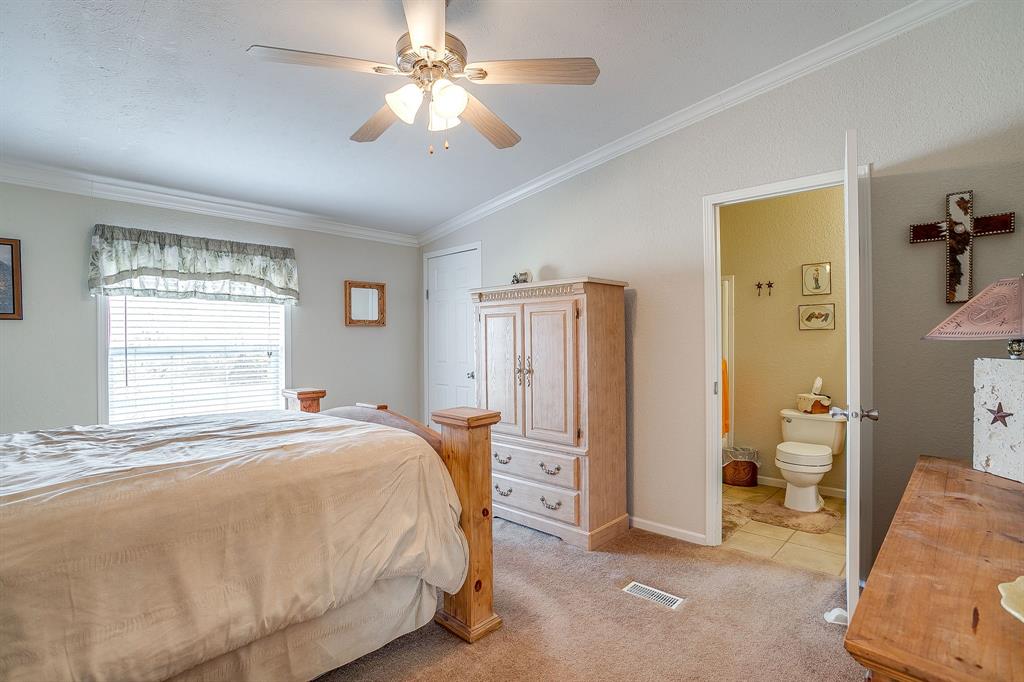 6724 Midway Road Springtown, TX 76082 - Photo 27 of 39 a spacious bedroom with a bed and a chandelier