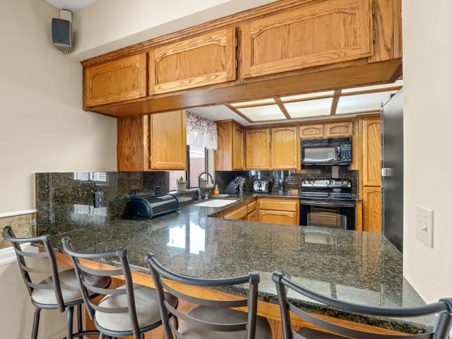 a kitchen with stainless steel appliances granite countertop a granite counter tops and a view of living room