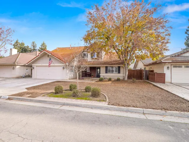 a front view of a house with a yard and potted plants