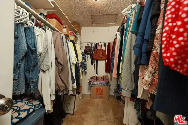 a view of walk in closet with clothes and shoes
