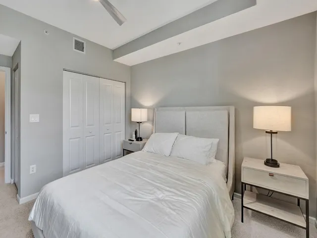 a bedroom with a bed and a potted plant on the dresser
