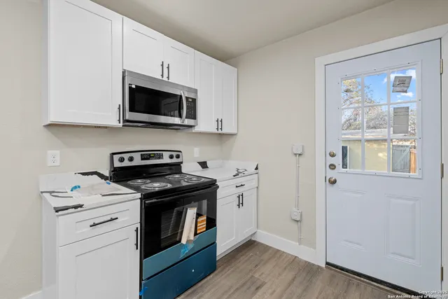 a kitchen with stainless steel appliances white cabinets and a stove top oven