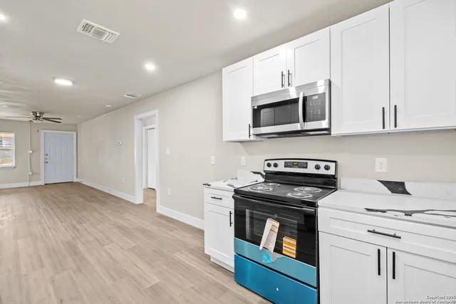 a kitchen with granite countertop cabinets stainless steel appliances and wooden floor
