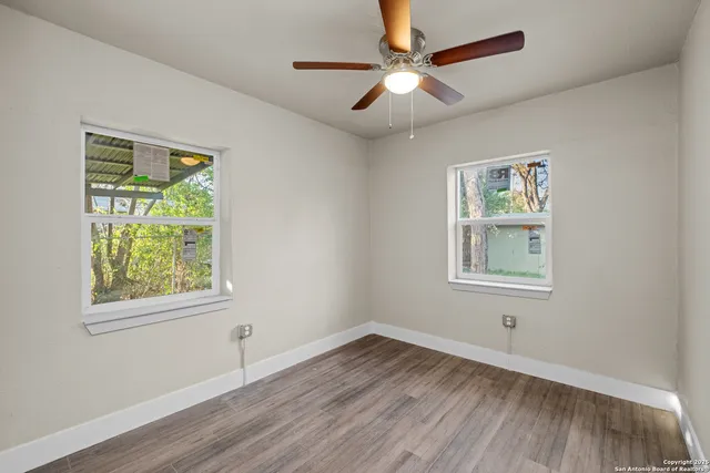 a view of an empty room with wooden floor and a window
