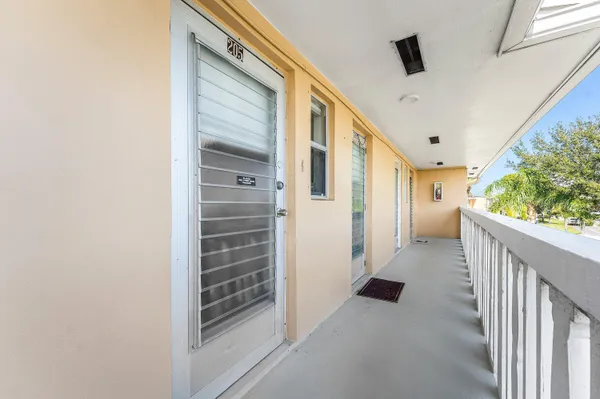 a view of a hallway to a bedroom with wooden floor and windows