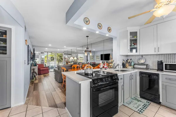 a view of a kitchen with stainless steel appliances granite countertop a stove cabinets and living room view