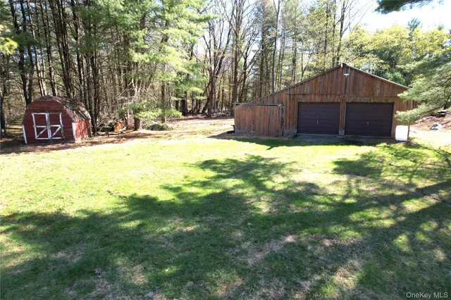 a front view of a house with a yard and covered with trees