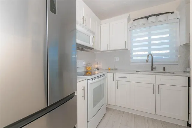 a kitchen with white cabinets and white appliances
