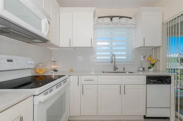 a kitchen with white cabinets and sink