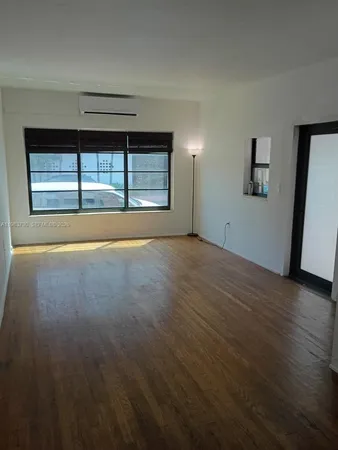 an empty room with wooden floor and a window
