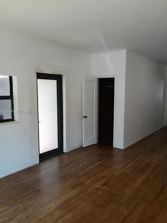 a view of an empty room with wooden floor and closet