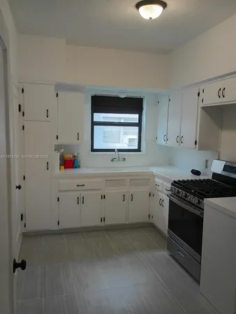 a kitchen with white cabinets and stove