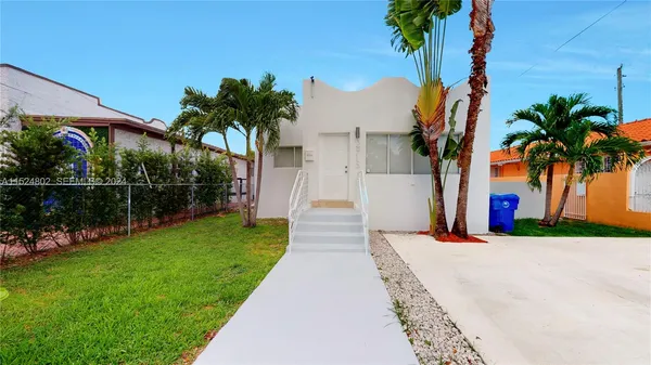 a front view of a house with a garden and palm trees