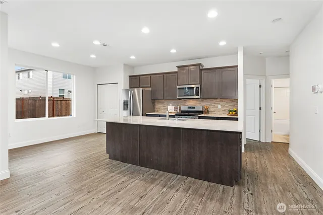 a kitchen with stainless steel appliances granite countertop a refrigerator a stove a sink and a oven with wooden floors