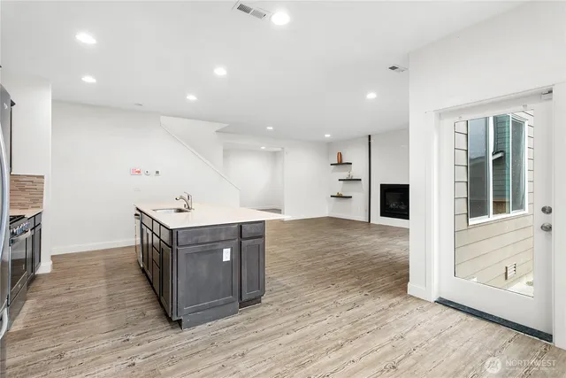 a view of kitchen with stainless steel appliances granite countertop a large counter top and wooden floors