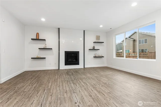 a view of empty room with wooden floor and kitchen