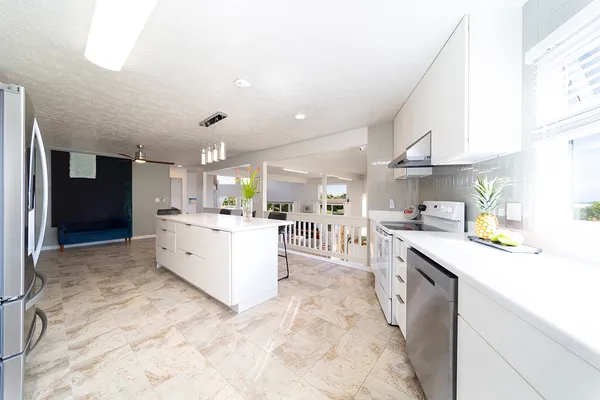 a large kitchen with stainless steel appliances kitchen island granite countertop a sink counter space and a view of living room
