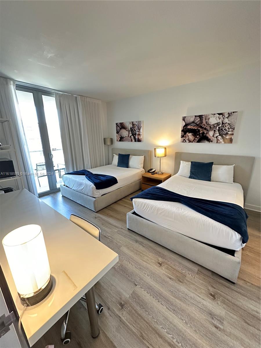 2602 East Hallandale Beach Boulevard, Unit R807 Hallandale Beach, FL 33009 - Photo 32 of 37 a bedroom with a bed and wooden floor