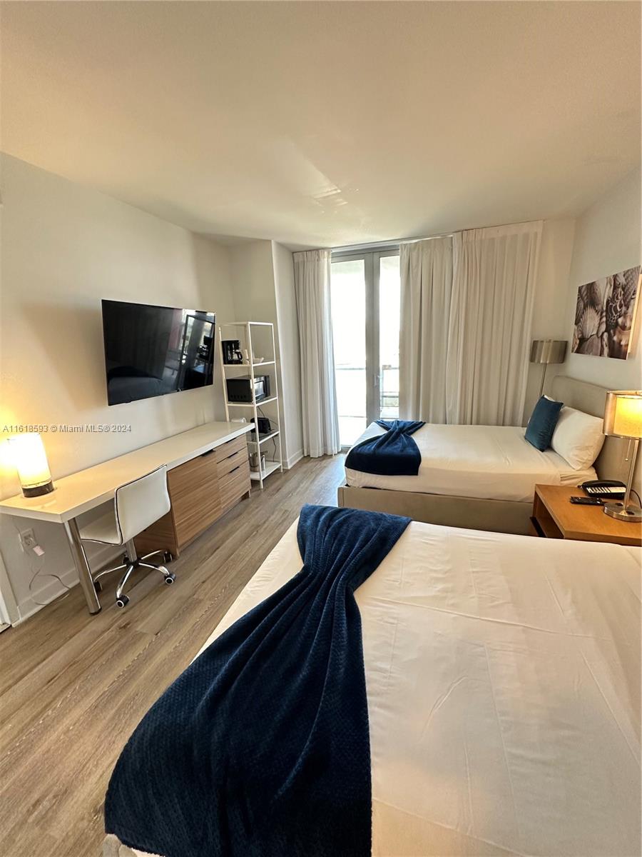 2602 East Hallandale Beach Boulevard, Unit R807 Hallandale Beach, FL 33009 - Photo 33 of 37 a bedroom with a bed a table and chair