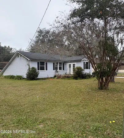 a front view of a house with a garden and trees