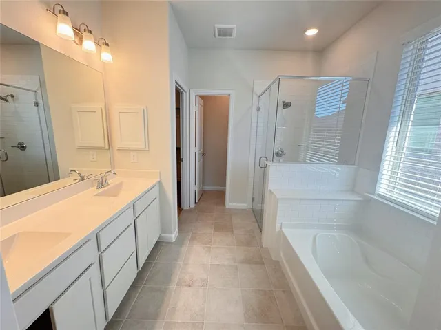 a spacious bathroom with a tub sink shower and mirror