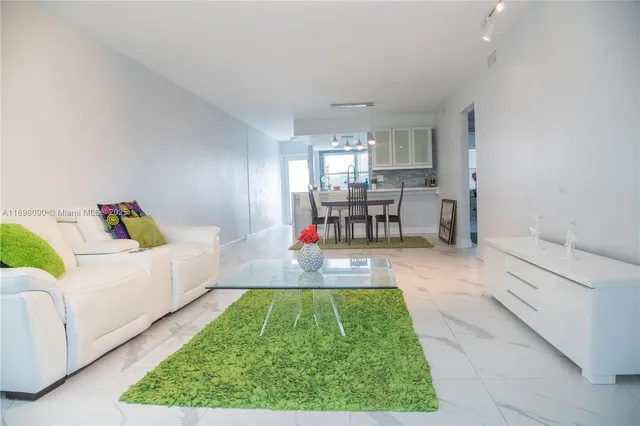 a living room with furniture and a dining table with kitchen view