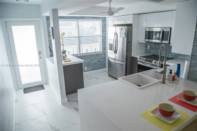 a kitchen with stainless steel appliances wooden floor and a refrigerator