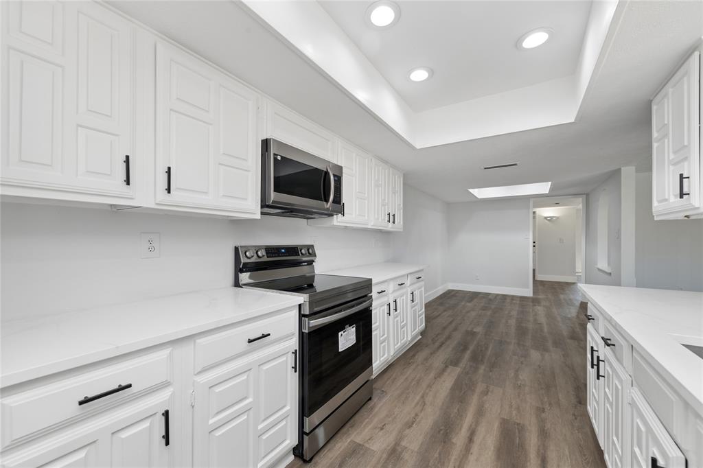 2119 Meadfoot Road Carrollton, TX 75007 - Photo 16 of 34 Kitchen featuring stainless steel appliances, white cabinets, dark wood-style floors, recessed lighting, and a tray ceiling