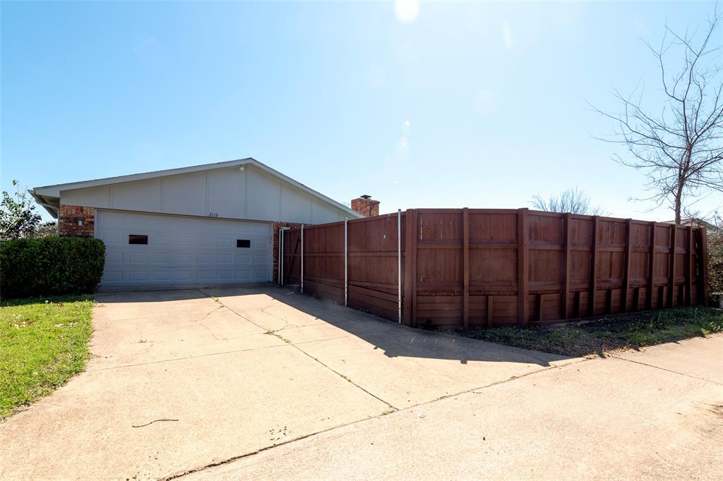 2119 Meadfoot Road Carrollton, TX 75007 - Photo 34 of 34 View of back of property featuring a garage, brick siding, concrete driveway, and board and batten siding