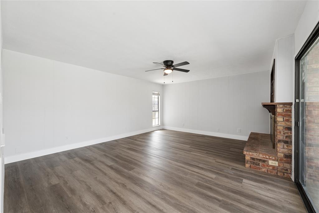 2119 Meadfoot Road Carrollton, TX 75007 - Photo 10 of 34 Unfurnished living room with a ceiling fan, dark wood-type flooring, and a fireplace