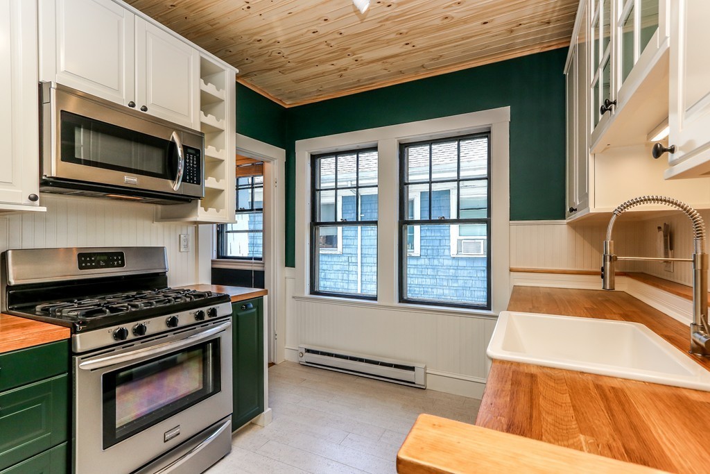 109 Adena Road, Unit 109 Newton, MA 02465 - Photo 13 of 23 a kitchen with stainless steel appliances a stove a microwave and cabinets