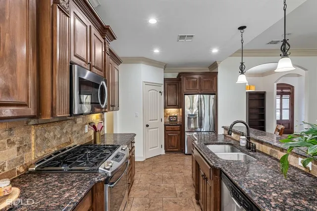 a kitchen with granite countertop kitchen island stainless steel appliances a sink stove and refrigerator