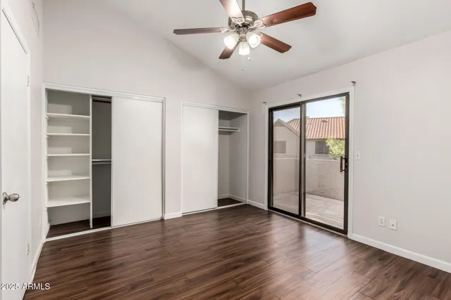 an empty room with wooden floor closet and windows