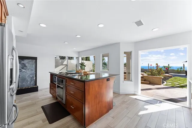 a kitchen with stainless steel appliances granite countertop a stove and a view of living room