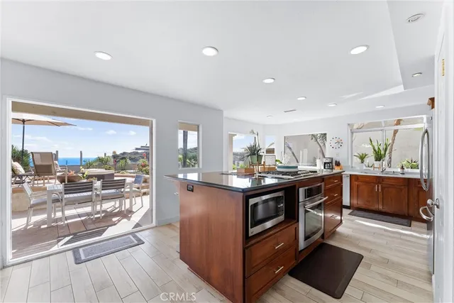 a kitchen with stainless steel appliances granite countertop a stove and a view of living room