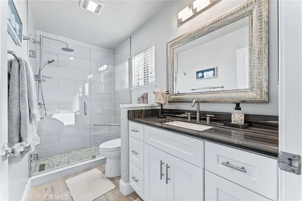 a bathroom with a double vanity sink toilet mirror and shower