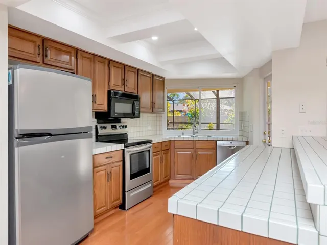 a kitchen with a refrigerator a sink dishwasher and a stove top oven with wooden floor