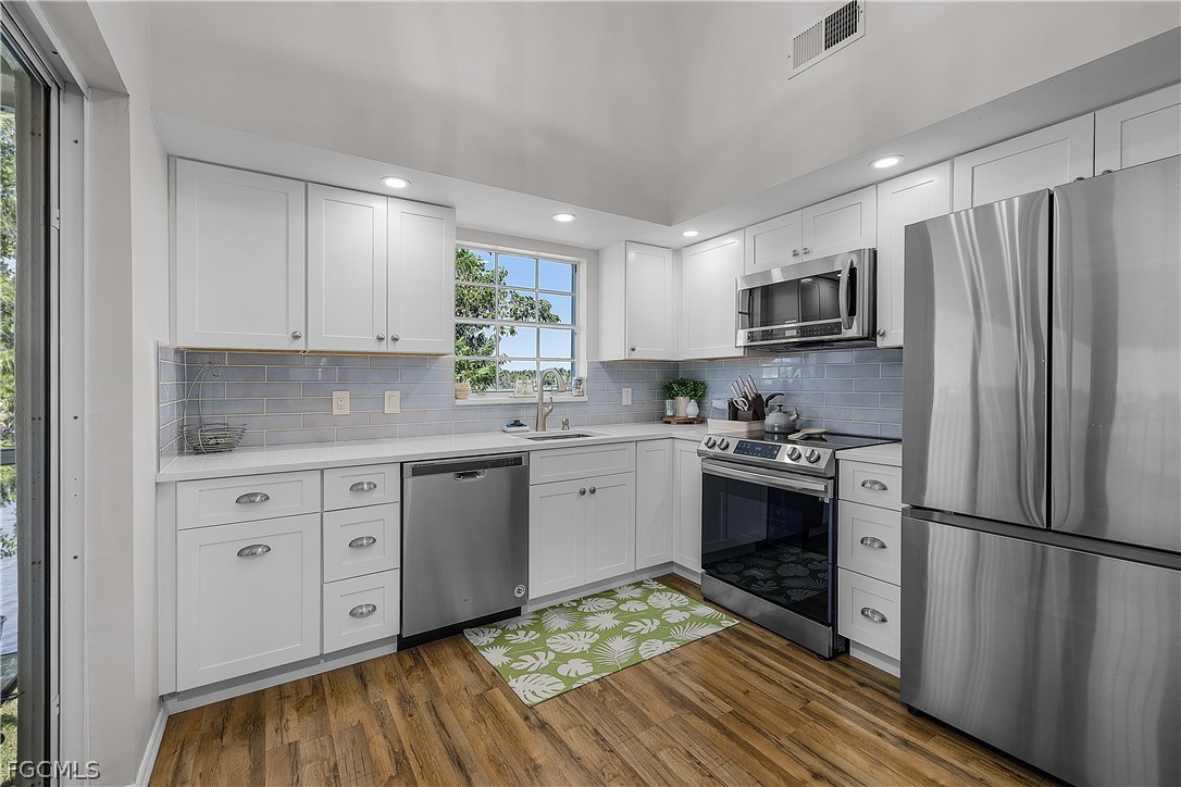 14983 Rivers Edge Court, Unit 232 Fort Myers, FL 33908 - Photo 9 of 27 a kitchen with stainless steel appliances white cabinets a sink a stove a refrigerator and cabinets