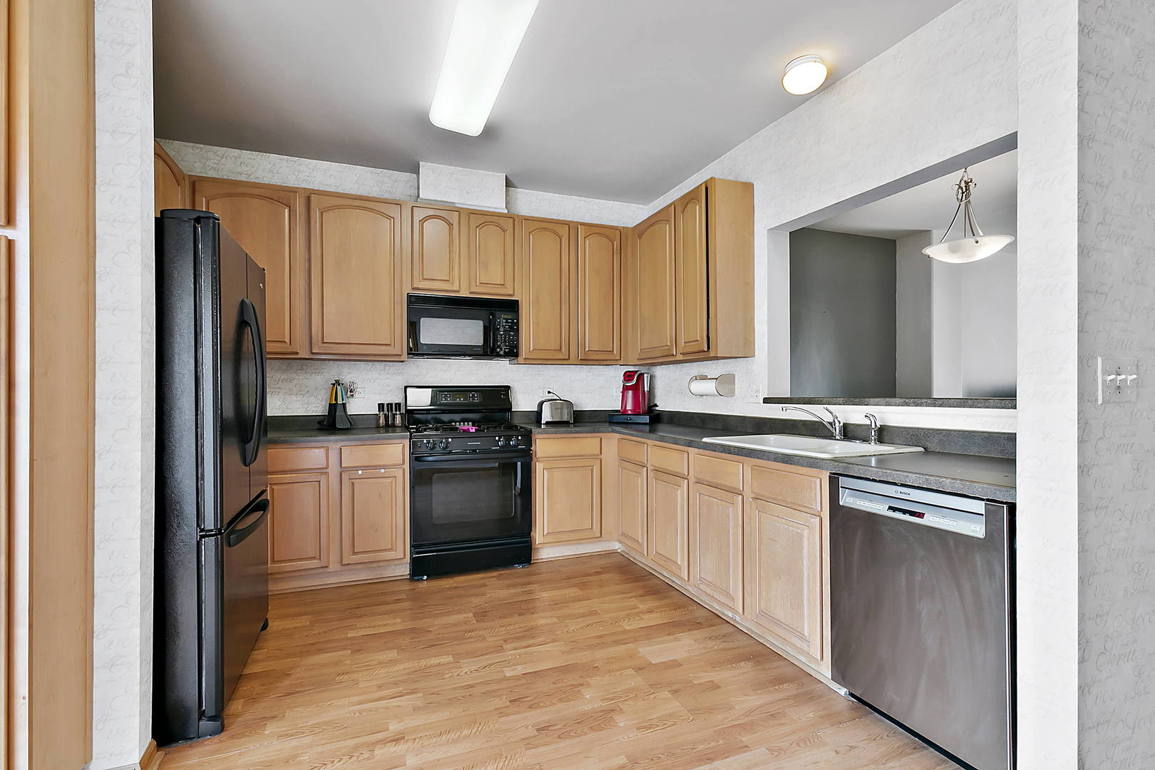 3459 Ravinia Circle, Unit 3459 Aurora, IL 60504 - Photo 7 of 18 a kitchen with granite countertop a stove top oven a sink dishwasher and a refrigerator with wooden floor