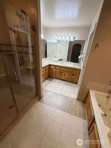 a bathroom with a tub a sink and glass door