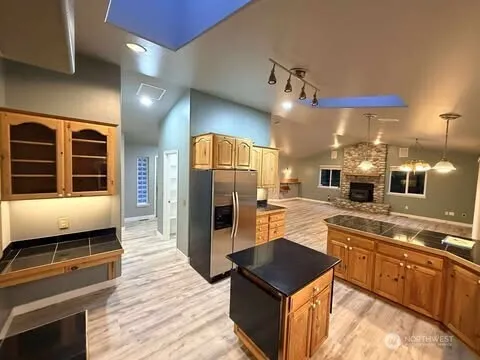 a kitchen with kitchen island granite countertop a refrigerator a oven a sink and dishwasher