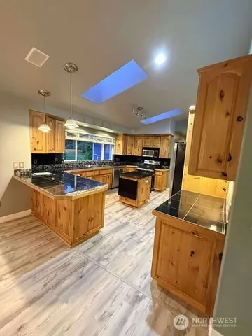 a kitchen with stainless steel appliances kitchen island granite countertop a stove and a refrigerator